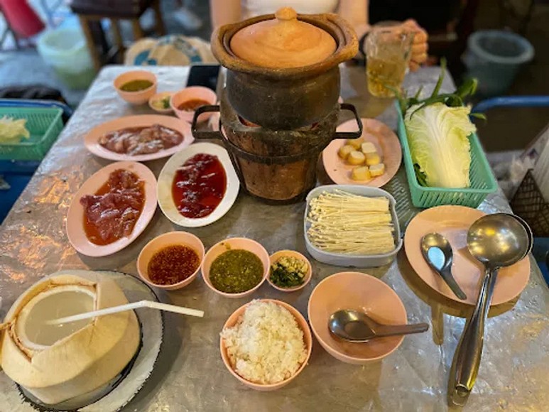 Bát lẩu Chiang Mai màu sẫm với nấm rừng và rau bản địa, khác rõ với Tom Yum Bangkok