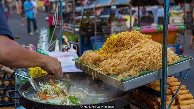 Xe đẩy Pad Thai vỉa hè Bangkok ban đêm, ánh đèn vàng, chảo khói bốc lên