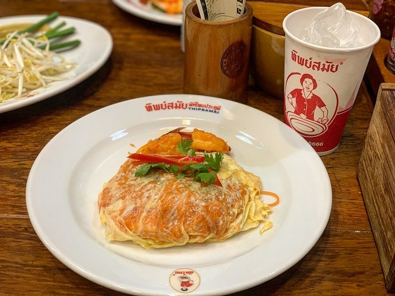 Đĩa Pad Thai bọc trứng kiểu Thip Samai, chụp từ trên xuống, nền gỗ tối