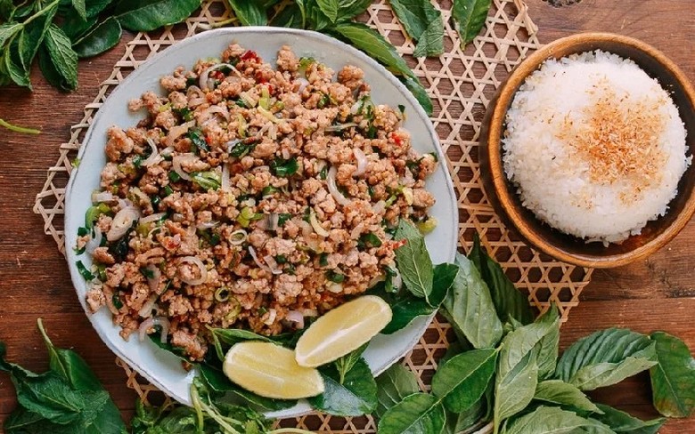 Đĩa larb thịt băm trộn thính ăn kèm rau sống và xôi
