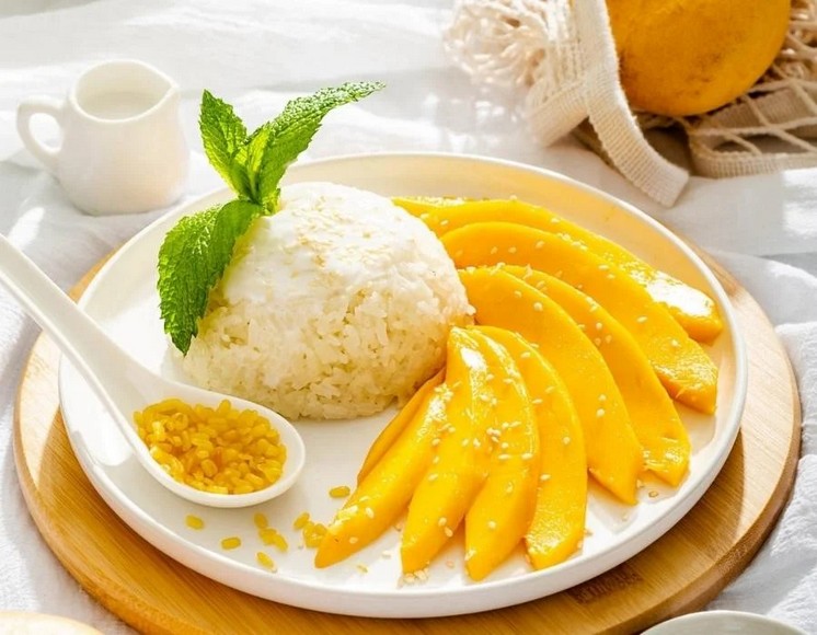 Đĩa xôi xoài Thái truyền thống với xoài vàng cắt lát, gạo nếp trắng và nước cốt dừa rưới trên bề mặt
